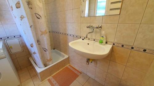 a bathroom with a sink and a mirror and a tub at Holiday home in Szantod - Balaton 20221 in Szántód