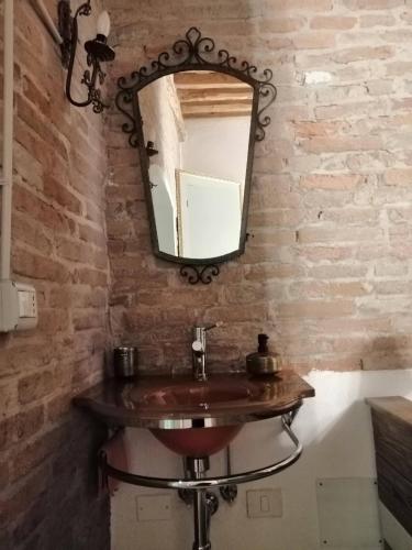 a bathroom with a sink and a mirror on a brick wall at Corte di Maggio B&B Country House in Imola