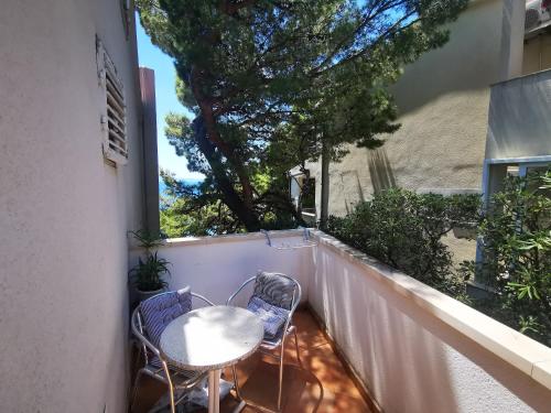 d'un balcon avec une table, des chaises et un arbre. dans l'établissement Villa Bose- Apartmani Luka Šodan, à Brela