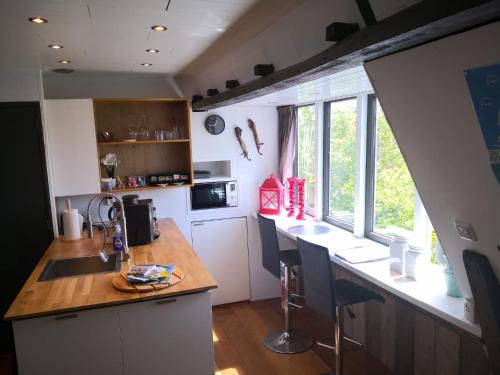 a kitchen with a counter and a kitchen island with chairs at WitteZwaan in Harlingen