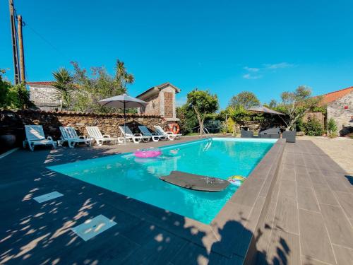 a swimming pool with chairs and umbrellas at Casa do Casal - Country House with Swimming Pool in Viana do Castelo