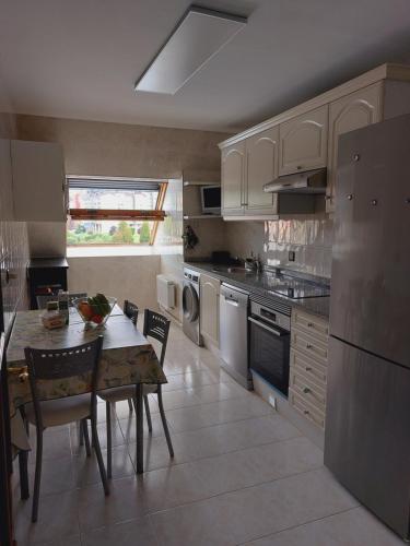 uma cozinha com uma mesa e cadeiras, um lavatório e um fogão em FOZANELDI OVIEDO. Céntrico, accesible desde autovía y con PARKING em Oviedo