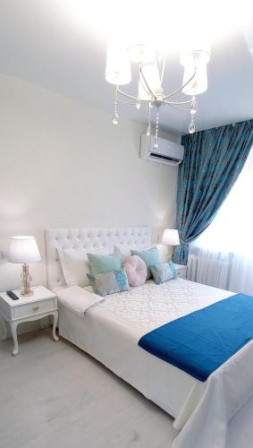 a bedroom with a large white bed with blue accents at Тіффані Апартаменти in Dnipro