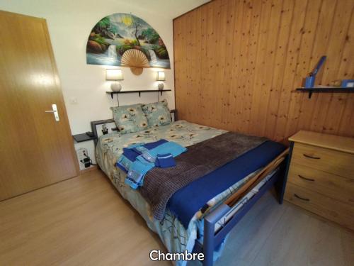 een slaapkamer met een bed en een houten muur bij Chez l'Eveline in Les Bois