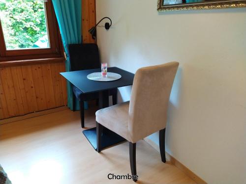 Una mesa negra con una silla y una taza. en Chez l'Eveline, en Les Bois
