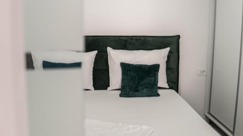 a white bed with two pillows and a green headboard at Toto’s Apartment in Constanţa