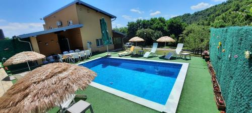 a swimming pool with chairs and umbrellas next to a house at Villa Meli in Visoko
