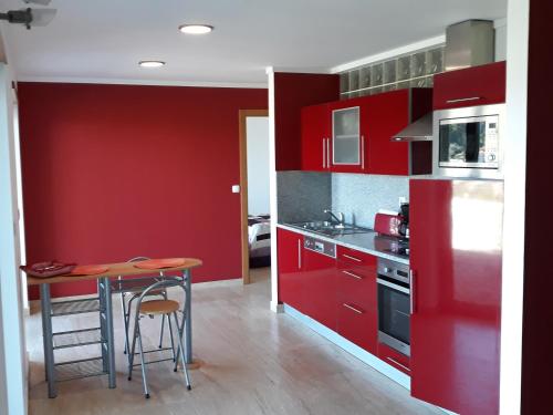 a kitchen with red cabinets and a table in it at Portela susa in Portela Susã