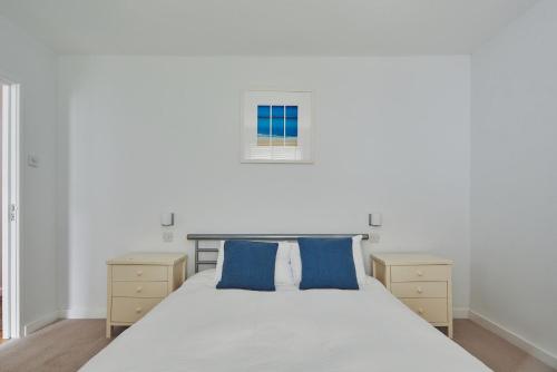 a bedroom with a large white bed with blue pillows at The New Pin in St Ives