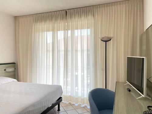 una camera da letto con un letto e una scrivania con una televisione di Hotel Garden ad Albissola Marina