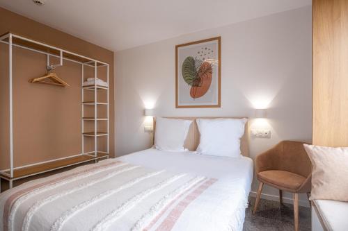 1 dormitorio con 1 cama blanca y 1 silla en The Originals Boutique Hôtel Amiens Sud, en Amiens