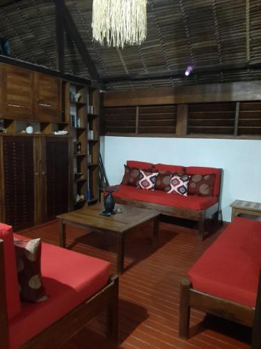 a living room with a red couch and a table at Le Moya Beach in Nosy Be