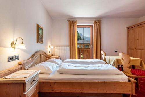 a bedroom with a bed and a table and a window at Hotel Residence Gardena Sella in Santa Cristina Gherdëina