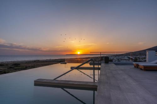 a sunset over the ocean with a swimming pool at Zahara Beach & Spa by QHotels - Adults Recommended in Zahara de los Atunes