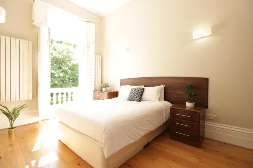 um quarto com uma cama grande e uma janela em Queen Victoria Apartments em Londres