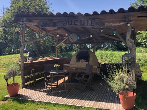 a wooden deck with a grill under a pergola at Les Robinsonades in Couladère