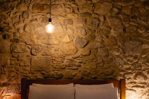 a stone wall with a bed and aendant light at Bravissimo Les Rajoles, Unique 3-bedroom apartment in Girona