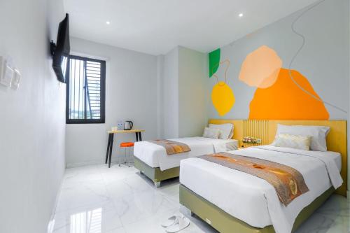 Habitación de hotel con 2 camas y pared de color naranja en Genio Inn - MANTOS, en Manado