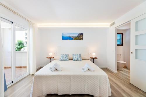 een witte slaapkamer met een groot bed met 2 kussens bij Albercutx Pollentia 2 in Port de Pollença