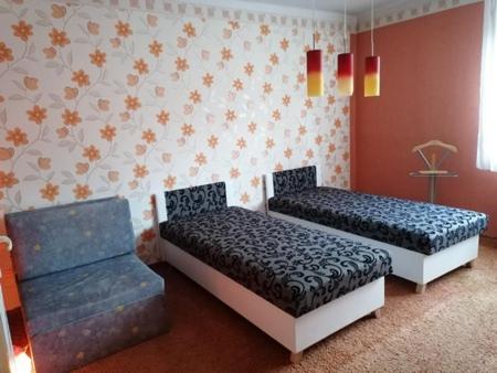 a room with two beds and a chair at Erzsébet Vendégház in Szarvas