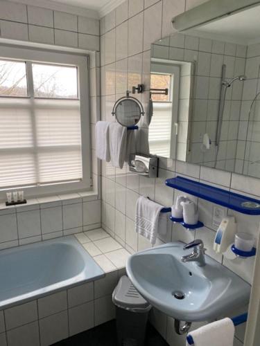 ein Badezimmer mit einem Waschbecken, einer Badewanne und einem Spiegel in der Unterkunft Schlosshotel Landstuhl in Landstuhl