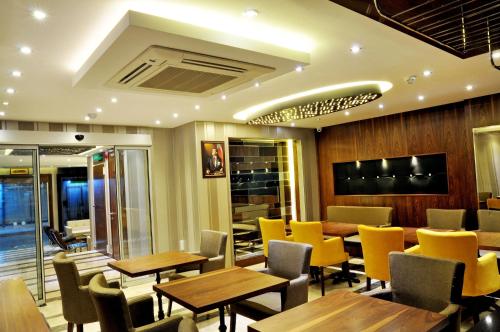 a restaurant with wooden tables and yellow chairs at Avin Hotel in Izmir