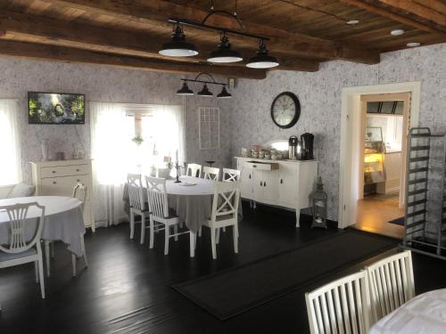 uma cozinha e sala de jantar com mesas e cadeiras brancas em Bredsjö Gamla Herrgård White Dream Mansion em Hällefors