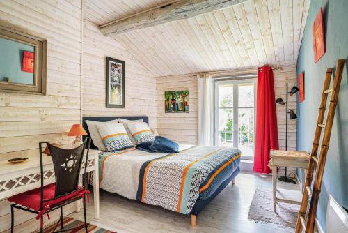 a bedroom with a bed and a red chair at Le Moulin de Pilet in Mortagne-sur-Sèvre