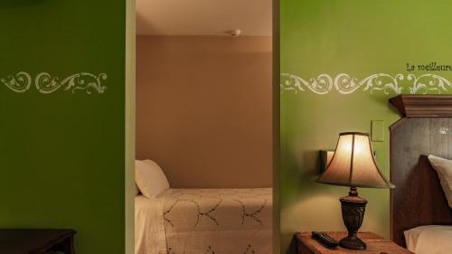 a bedroom with green walls and a lamp on a table at Auberge Akamaraska in Kamouraska