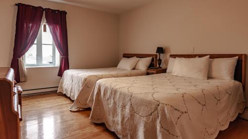 a bedroom with two beds and a window at Auberge Akamaraska in Kamouraska