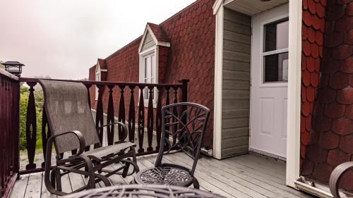 a deck with chairs and a white door on a house at Auberge Akamaraska in Kamouraska