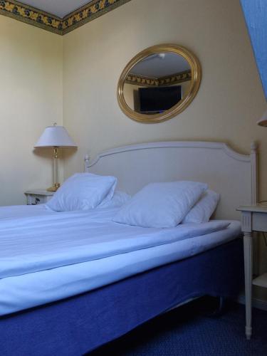 a bed with white pillows and a mirror on the wall at Best Western Motala Stadshotell in Motala