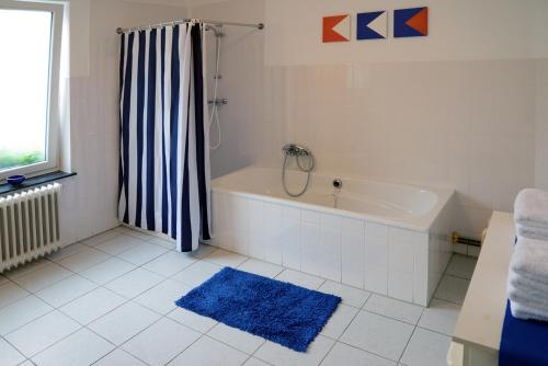 een badkamer met een bad en een blauw tapijt bij Casa al Mulino in Valkenburg