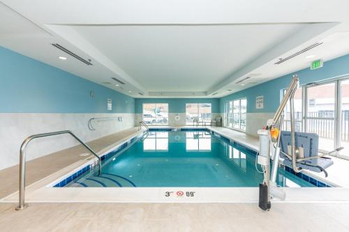 a swimming pool in a building with blue walls at Holiday Inn Express & Suites Charlottesville by IHG in Charlottesville