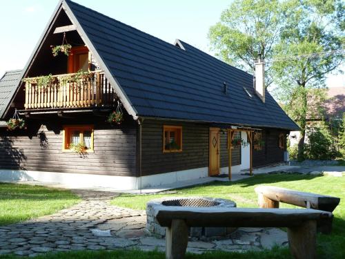 a wooden house with a balcony and a bench at Drevenica pod Lánom in Zuberec