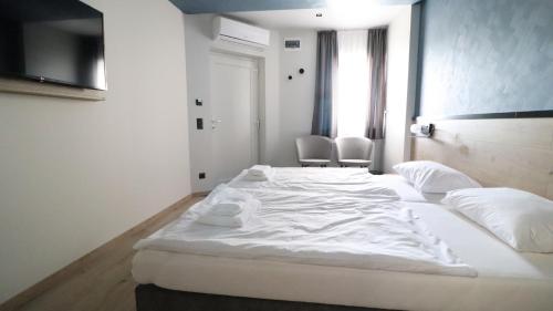a large white bed in a room with two chairs at Jam Panzió in Kapuvár