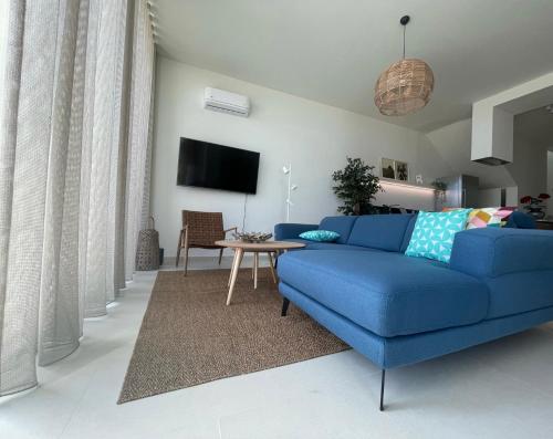 a living room with a blue couch and a table at 3-bedroom beach villa with a pool and private sauna in Green Coast Palase in Palasë