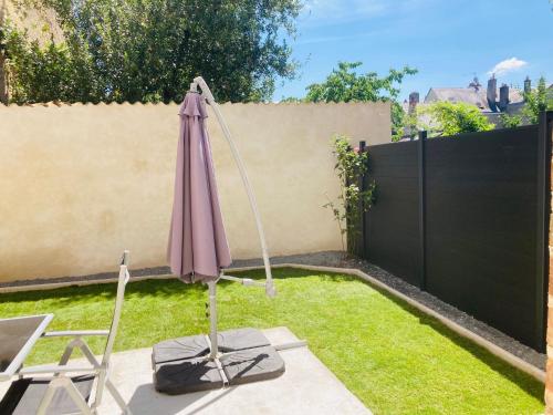 an umbrella in a garden with a fence at Centre ville (1) : superbe appartement climatisé in La Flèche