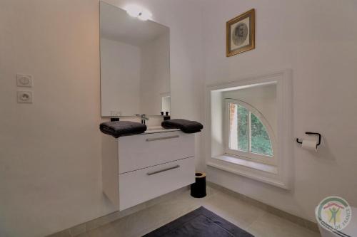 un bagno bianco con lavandino e finestra di Manoir Les Brieux a Plélan-le-Grand