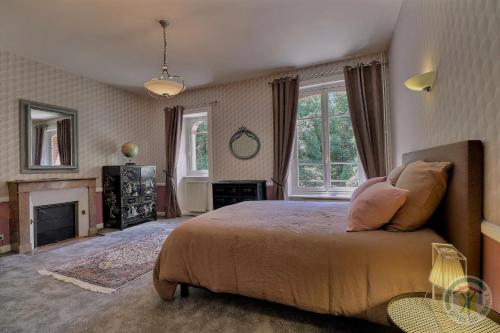 una camera con un grande letto e un camino di Manoir Les Brieux a Plélan-le-Grand