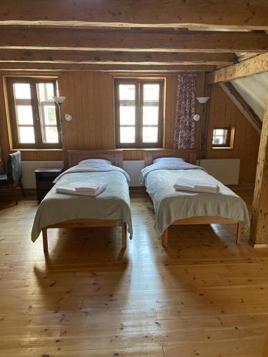 two beds in a room with wooden floors and windows at Kapteinis in Liepāja