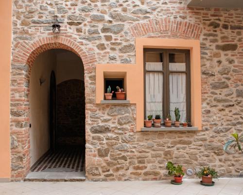 um edifício de tijolos com duas janelas e vasos de plantas em La Corte em Arezzo