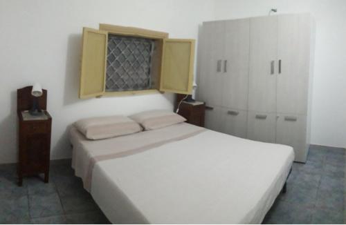 a bedroom with a white bed and a window at Casa vacanze immersa nelle campagne salentine in Monacizzo