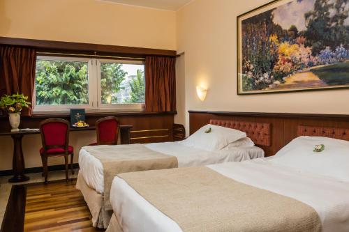a hotel room with two beds and a window at Santa Barbara Hotel in San Donato Milanese