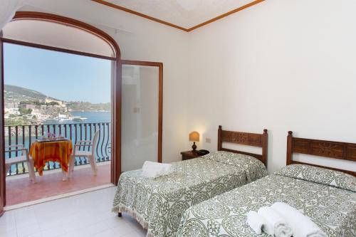 1 dormitorio con 2 camas y balcón con vistas. en Hotel Carasco en Lipari