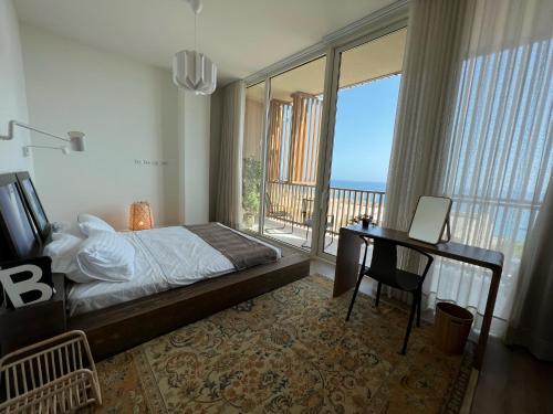 a bedroom with a bed and a desk and a balcony at 3-bedroom beach villa with a pool and private sauna in Green Coast Palase in Palasë