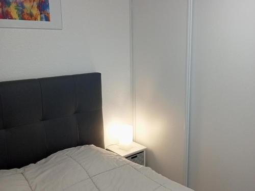 - une chambre avec un lit et une lampe sur une table de chevet dans l'établissement Studio mezzanine cosy à La Rochelle proche plage - FR-1-551-53, à La Rochelle