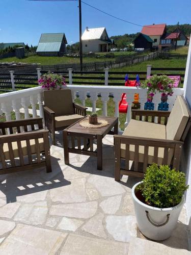 a patio with two benches and a table and a fence at White Home in Žabljak