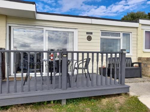 a deck with chairs and a table in front of a house at Sunset 128 Sandown Bay Holiday Centre Generous Ferry Saving! in Sandown