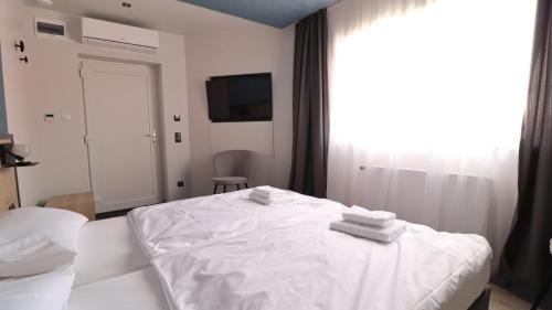 a bedroom with a white bed with towels on it at Jam Panzió in Kapuvár